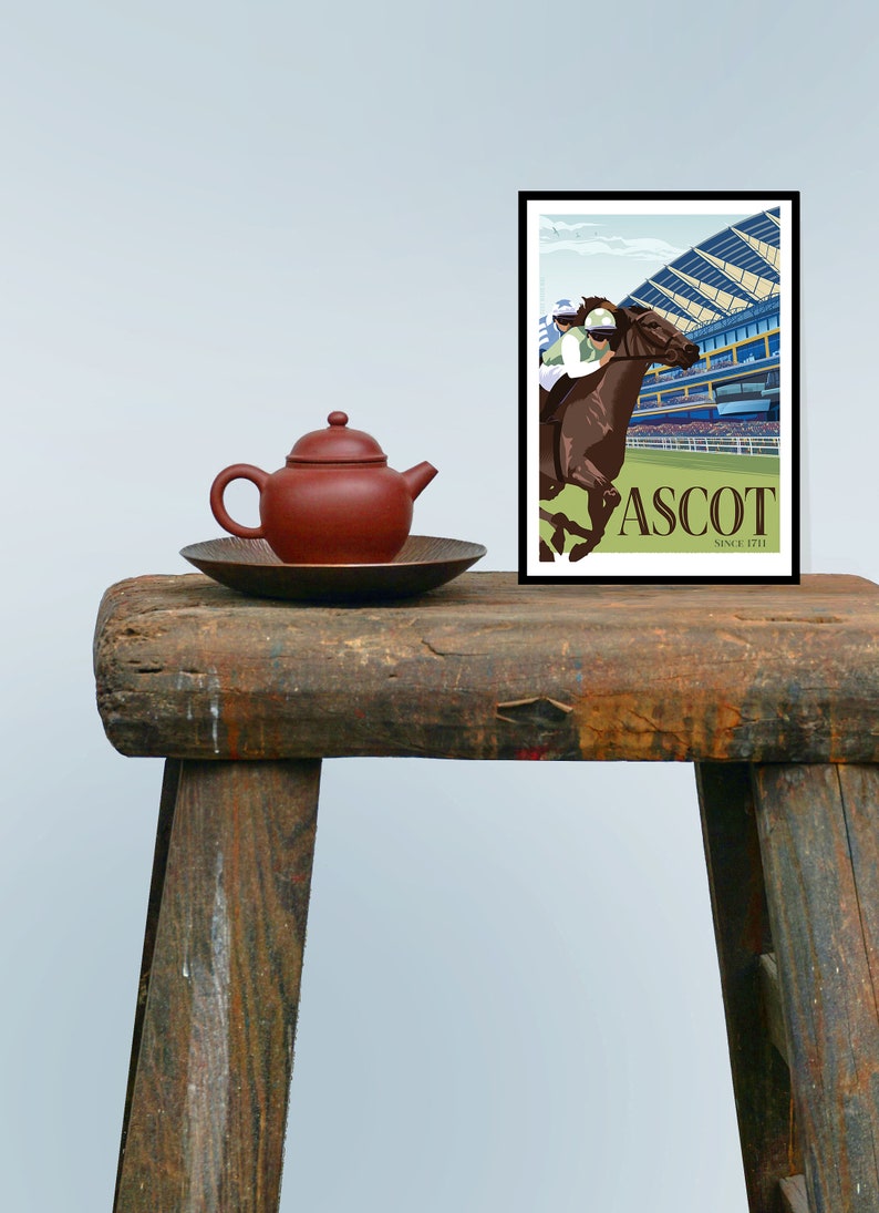 May include: A framed poster with a horse racing scene at Ascot. The artwork features a brown horse with a jockey, set against a backdrop of a grandstand. A small, red teapot and a dark brown plate sit on a rustic wooden stool.