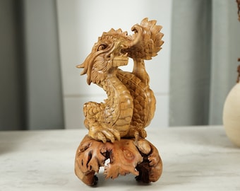 May include: A wooden carving of a golden dragon with intricate details, perched on a natural wood base. The dragon is curled up with its head turned to the side, and its claws are visible.