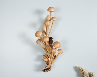 May include: A wooden wall sculpture of a cluster of mushrooms, carved in a natural brown color. The mushrooms are arranged in a cascading pattern, creating a whimsical and organic design.