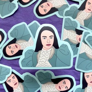 May include: A sticker featuring a cartoon illustration of a woman with dark hair wearing a light blue dress with white lace trim. The woman has a serious expression on her face.