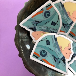 May include: A set of four stickers featuring a stylized illustration of a person wearing a helmet with a blue and orange color scheme. The stickers are printed on white paper.