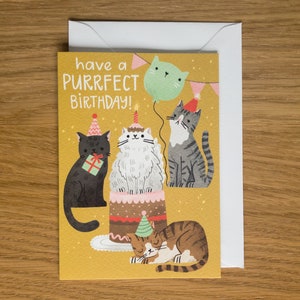 May include: A yellow birthday card with the text "have a purrfect birthday!" and a cartoon illustration of four cats celebrating with a cake and a balloon.