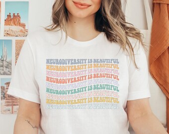 May include: White t-shirt with the text "Neurodiversity is Beautiful" repeated in rainbow colors.