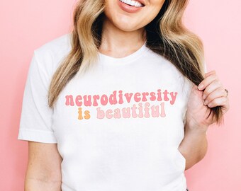May include: A white t-shirt with the text "neurodiversity is beautiful" in pink and orange letters.