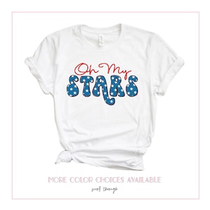 May include: White t-shirt with red and blue text that says "Oh My Stars". The text is in a retro font and has a blue and white star pattern.