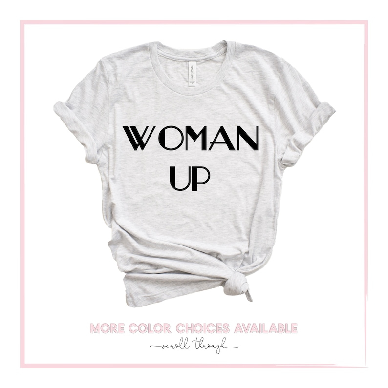 May include: A gray t-shirt with the text "WOMAN UP" printed in black.