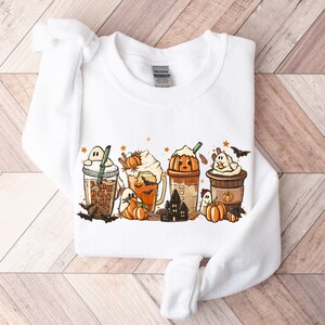 May include: White sweatshirt with a graphic of pumpkin spice lattes and ghosts. The graphic includes the text "BOO!"