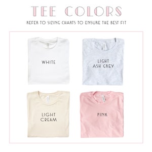 May include: Image showcasing four t-shirt color options: white, light ash grey, light cream, and pink. The text "TEE COLORS" and "REFER TO SIZING CHARTS TO ENSURE THE BEST FIT" are displayed at the top. Each shirt is neatly folded.