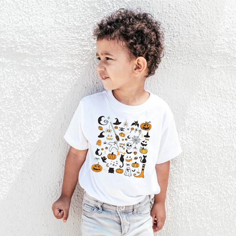 May include: A white t-shirt with a black and orange Halloween-themed print featuring pumpkins, ghosts, bats, spiders, and other spooky icons.
