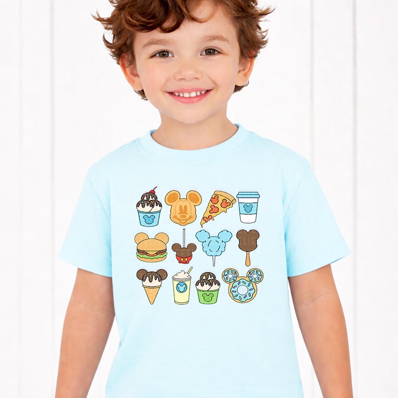May include: A light blue short-sleeve t-shirt featuring a grid of colorful food illustrations, including a Mickey Mouse-shaped waffle, pizza slice, burger, cotton candy, ice cream cone, donut, and various drinks, all with small Mickey icons.
