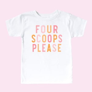 May include: A white short-sleeved t-shirt featuring the text FOUR SCOOPS PLEASE printed in a distressed, block-style font. The letters alternate between shades of pink and orange, creating a colourful graphic design on the front of the garment.