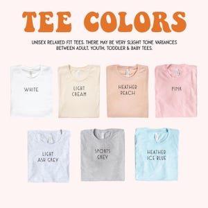 May include: Image showcasing a variety of tee shirt colors, including white, light cream, heather peach, pink, light ash grey, sports grey, and heather ice blue. The text "TEE COLORS" is displayed at the top.