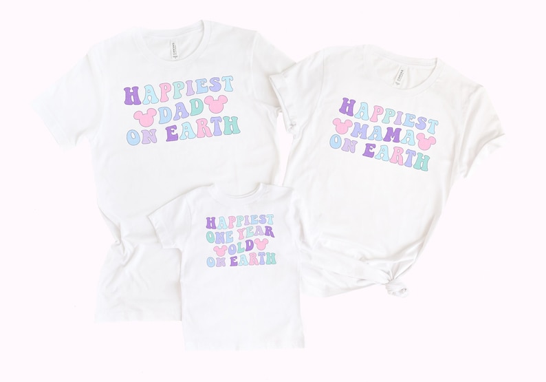 May include: Three white t-shirts with pastel colored text that reads "Happiest Dad on Earth", "Happiest Mama on Earth", and "Happiest One Year Old on Earth". Each shirt has a Mickey Mouse ear graphic.