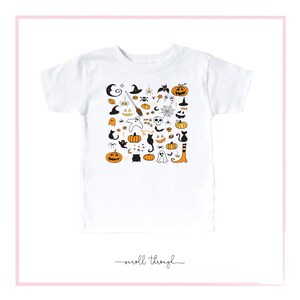 May include: White t-shirt with a black and orange Halloween-themed print. The print features pumpkins, ghosts, bats, cats, witches, and other Halloween symbols.