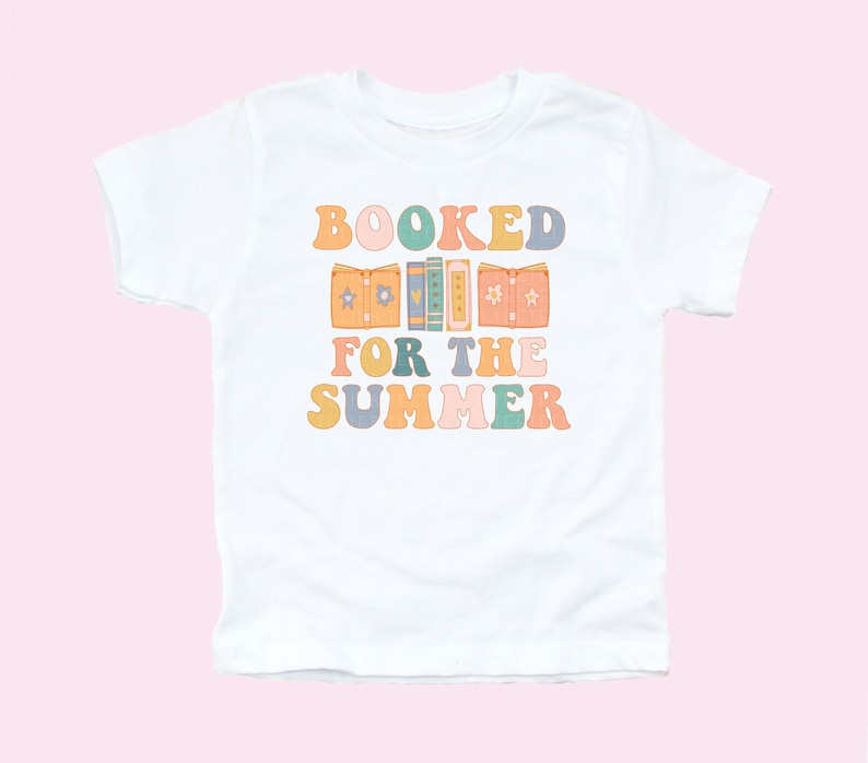 May include: White t-shirt with a colorful graphic that says "BOOKED FOR THE SUMMER" with a stack of books in the middle of the text.