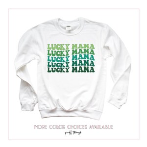 May include: White long-sleeved sweatshirt with the text "LUCKY MAMA" repeated five times in a green and blue gradient. The text is in a retro font style.