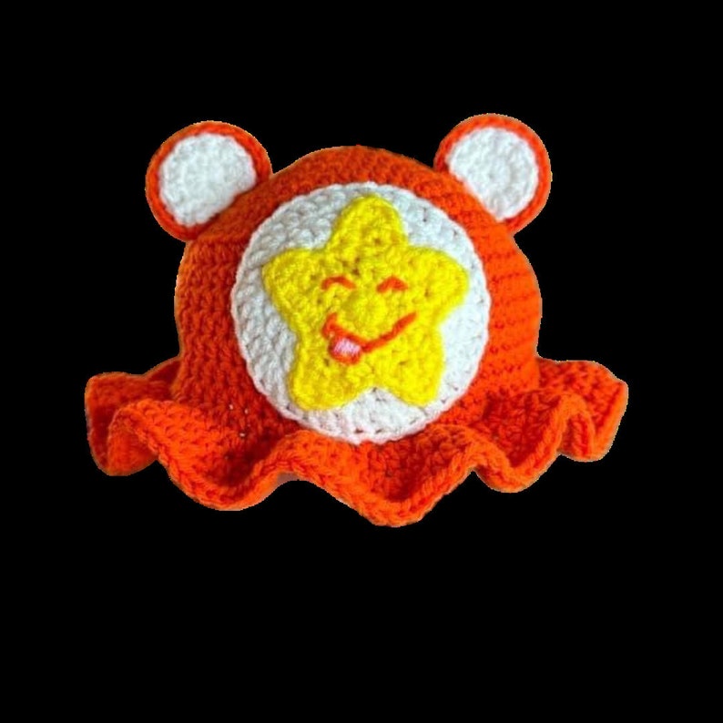 May include: Orange crocheted sun hat with white and yellow star detail. The star has a smiling face with a tongue sticking out.