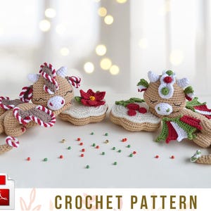 Op de afbeelding: Haakpatroon voor twee gemberdraken amigurumi-speelgoed. De draken zijn bruin met rode en witte pepermuntaccenten en groene hulstaccenten. Ze liggen op gemberkoekjes met rode en groene sprinkels.