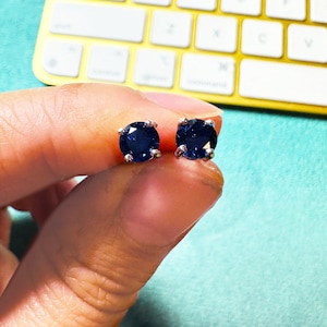 May include: A pair of silver stud earrings with dark blue round gemstones.