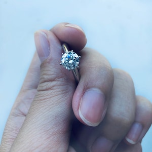 May include: A silver ring with a large, round, clear diamond.