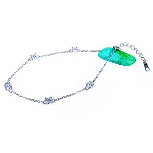 May include: A delicate silver chain bracelet with five small, clear, round stones set in a flower shape.