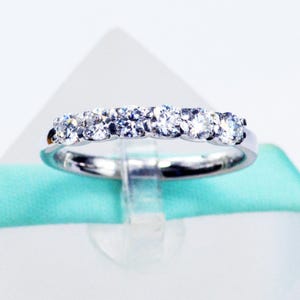 May include: A silver band ring with a row of clear round cubic zirconia stones.