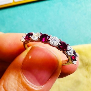 Peut inclure: Une bague en argent avec des rubis rouges et des diamants ronds transparents alternés.