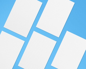 Op de afbeelding: Vijf witte vellen papier met verschillende patronen op een lichtblauwe achtergrond. De vellen zijn gestreept, geruit en gestippeld.