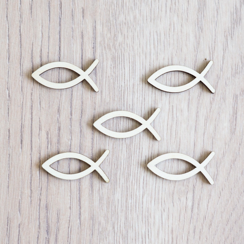 Peut inclure: Six symboles de poissons en bois blanc sur un fond en bois clair. Les symboles de poissons sont tous de la m&ecirc;me taille et de la m&ecirc;me forme, et ils sont dispos&eacute;s de mani&egrave;re al&eacute;atoire.