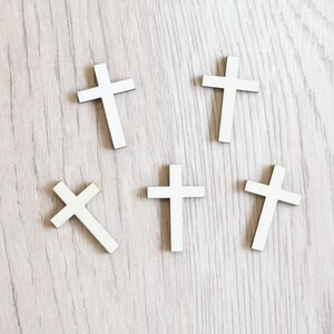 Peut inclure: Cinq croix en bois blanc sur un fond en bois clair. Les croix sont toutes de la m&ecirc;me taille et de la m&ecirc;me forme.