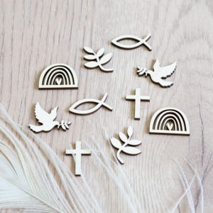 Peut inclure: Un ensemble de d&eacute;coupes en bois repr&eacute;sentant des symboles chr&eacute;tiens, notamment une colombe, un arc-en-ciel, un poisson, une croix et une branche. Les d&eacute;coupes sont peintes en blanc et dispos&eacute;es sur une surface en bois brun clair.