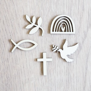 Peut inclure: Ensemble de six formes d&eacute;coup&eacute;es en bois blanc, comprenant une croix, une colombe avec une branche d'olivier, un poisson, un arc-en-ciel avec un c&oelig;ur et deux branches de feuilles.