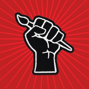 May include: A black fist holding a white paintbrush, against a red background with white radiating lines.