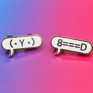 Puede incluir: Dos pines de esmalte de color dorado con fondo blanco y texto negro. El primer pin dice "( . Y . )" y el segundo pin dice "8===D".
