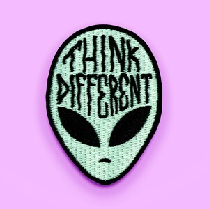 May include: A green alien-shaped patch with black embroidery that reads "Think Different".