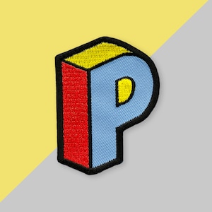 Könnte beinhalten: Ein gestickter Aufnäher in Form des Buchstabens "P" in Blau, Gelb und Rot.