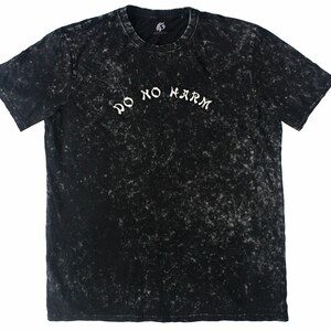 May include: Black t-shirt with a white "Do No Harm" inscription in a stylized font. The shirt has a distressed, acid-washed look.
