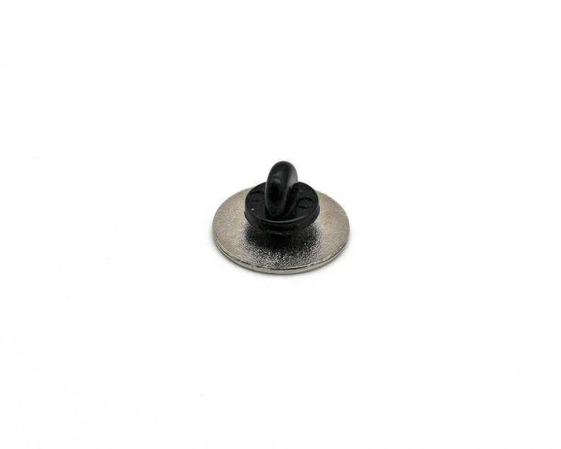 May include: The back of a silver pin with a black metal clasp.