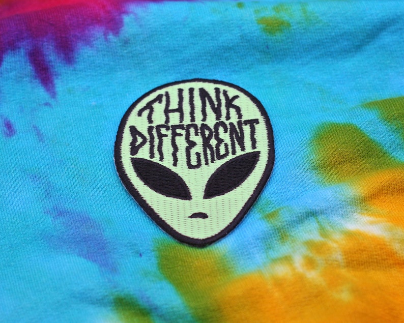 May include: Green alien head embroidered patch with the text "Think Different" in black.