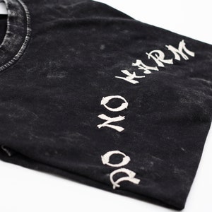 May include: Black t-shirt with a white "DO NO HARM" graphic printed on the sleeve.