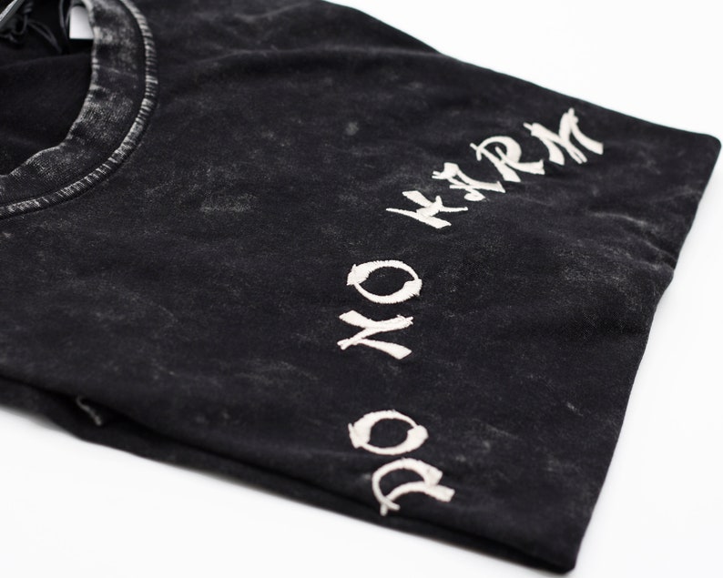 May include: Black t-shirt with a white "DO NO HARM" graphic printed on the sleeve.