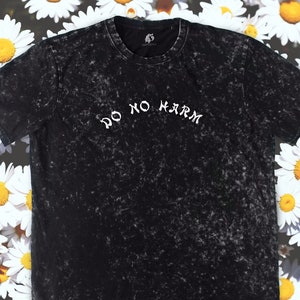 May include: Black t-shirt with a white distressed print that says "Do No Harm" on a black background.