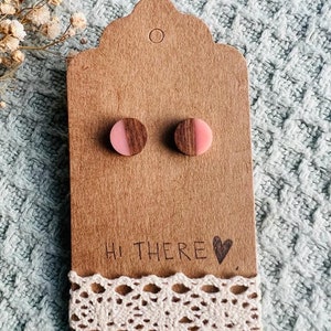 May include: A pair of wooden stud earrings with a pink and brown half-circle design. The earrings are displayed on a brown card with the text "Hi there &hearts;".