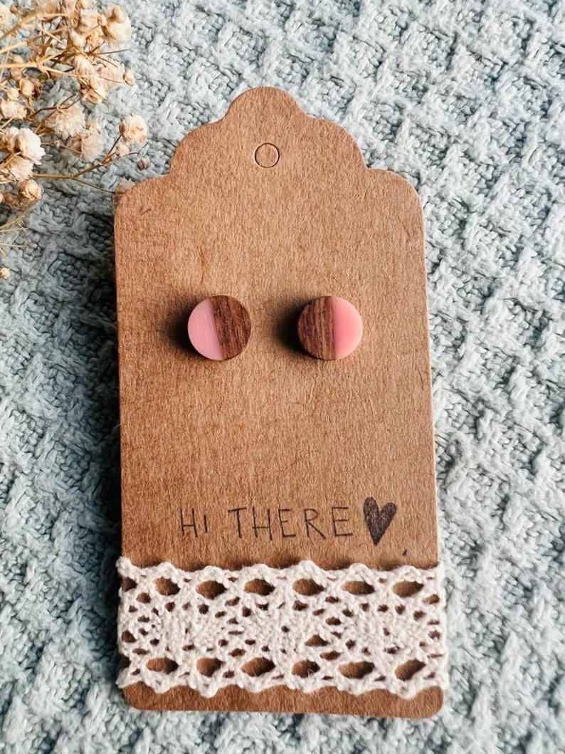 May include: A pair of wooden stud earrings with a pink and brown half-circle design. The earrings are displayed on a brown card with the text "Hi there &hearts;".