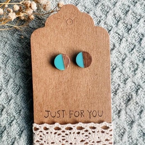 May include: A pair of turquoise and brown wood earrings. The earrings are round and have a half-circle of turquoise resin on top of the wood. The earrings are on a brown card with the text "JUST FOR YOU".