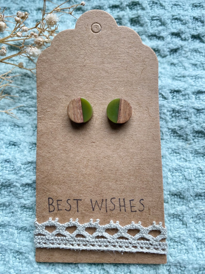 May include: A pair of green and brown wood and resin stud earrings on a brown card with the text "BEST WISHES".