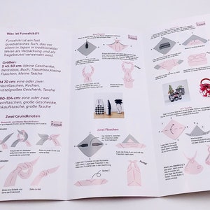 May include: An open brochure with instructions on how to use a Furoshiki cloth, a traditional Japanese wrapping cloth. The brochure includes diagrams and text in German, with measurements in centimeters.