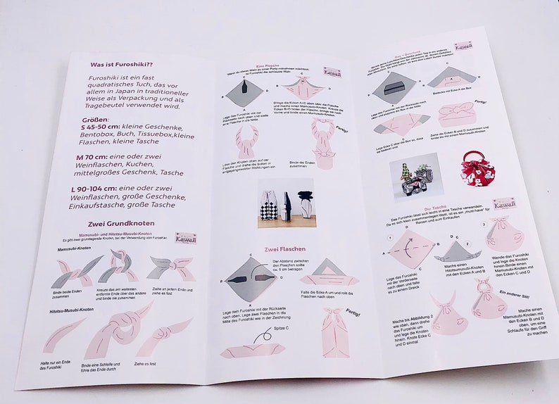 May include: An open brochure with instructions on how to use a Furoshiki cloth, a traditional Japanese wrapping cloth. The brochure includes diagrams and text in German, with measurements in centimeters.