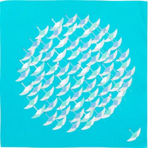 May include: A square, turquoise-colored scarf featuring a flock of stylized white and blue birds in flight. The birds are arranged in a circular pattern, with one bird flying solo in the lower right corner. The scarf is made of a soft material.