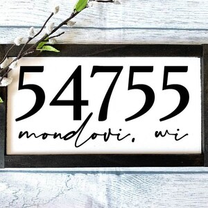 May include: Black and white house number sign with the number 54755 and the text "Mondovi, WI" on a white background with a black frame.